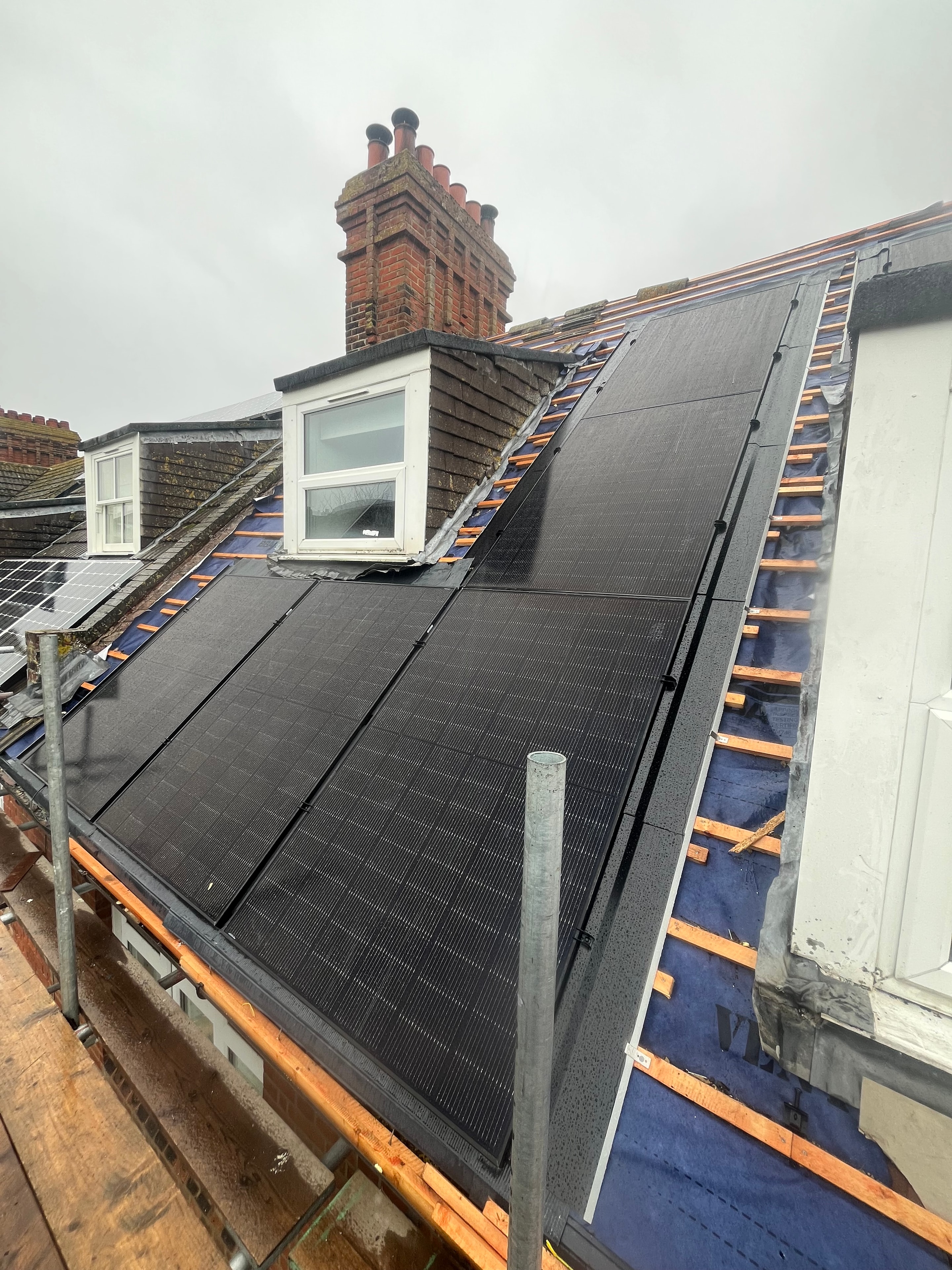Black solar panels on slate roof during installation